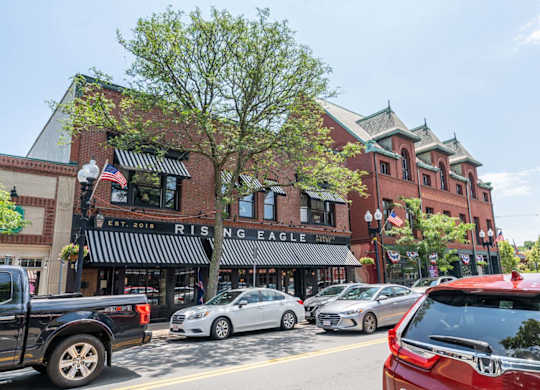 Downtown Melrose street with cars parked on the side of the road and a brick building