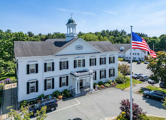 A white building with a green dome and an American flag on top.