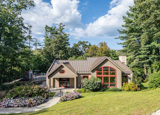 the front of a house with a lawn and trees