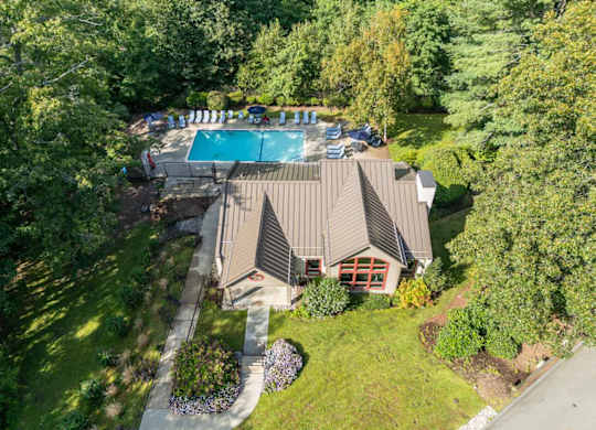 an aerial view of a house with a swimming pool and a yard with chairs