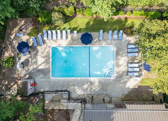 an aerial view of a pool with umbrellas and chairs around it