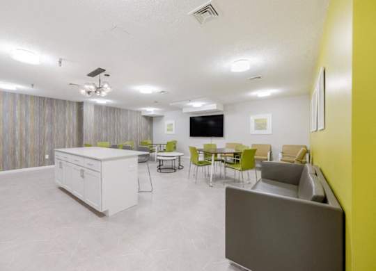 A Community Room with a table and chairs and a kitchen at North Stoughton Village Apartments in Stoughton, MA
