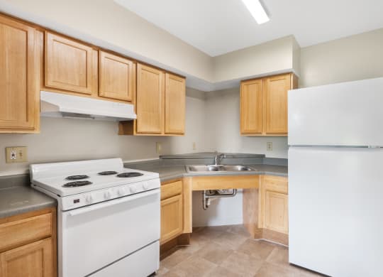 A kitchen with white appliances and wooden cabinets at Shoreline Apartments Buffalo NY.