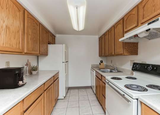 a kitchen with white appliances and wooden cabinets at Bates Hill Apartments Pittsburgh, PA.