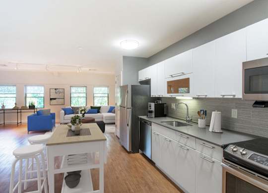 a kitchen and living room with white cabinets and a table and chairsat Ames Shovel Works Apartments, Massachusetts, 02356