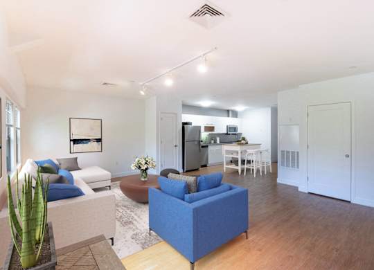 a living room with couches and a table with a kitchen in the backgroundat Ames Shovel Works Apartments, North Easton, MA