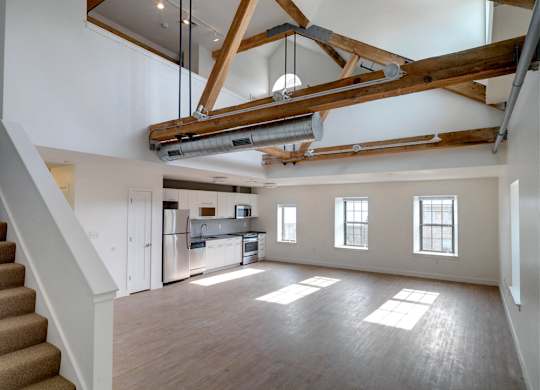 Living room and kitchen with wood flooring at Ames Shovel Works Apartments, North Easton, MA, Massachusetts