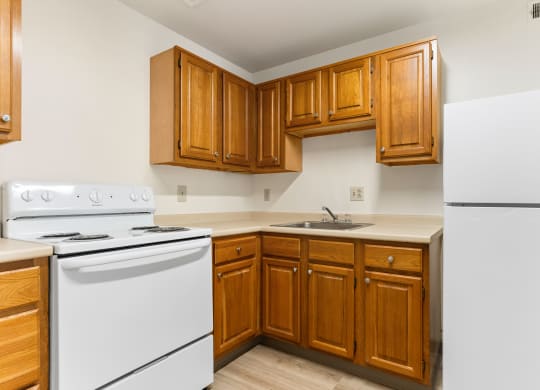 A kitchen with white appliances and wooden cabinets at Huntingdon Village Hunker, PA.