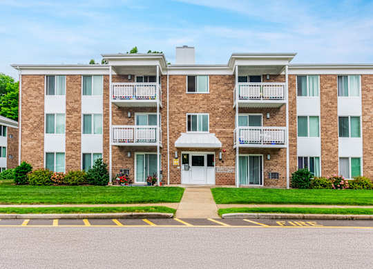 an apartment building with a sidewalk and grassat North Stoughton Village, Stoughton, Massachusetts