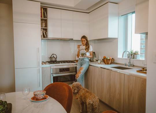 A woman is standing in a kitchen with a dog.