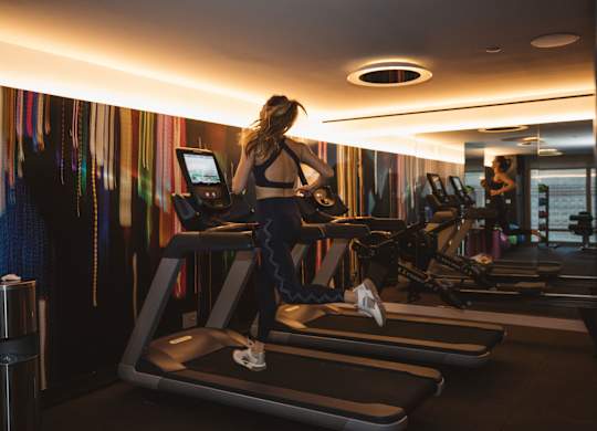 A woman is running on a treadmill in a gym.
