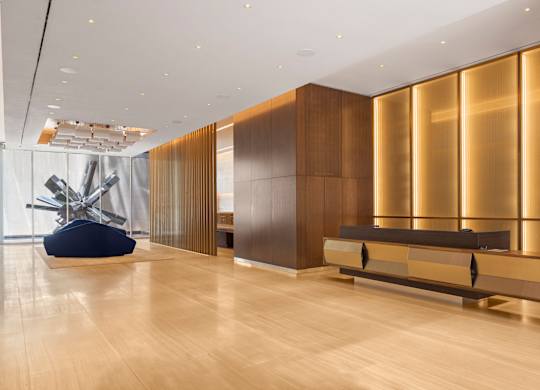 A room with a wooden floor and a bench with a gold panel behind it.