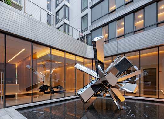A large metal sculpture in the foreground of a modern building lobby.
