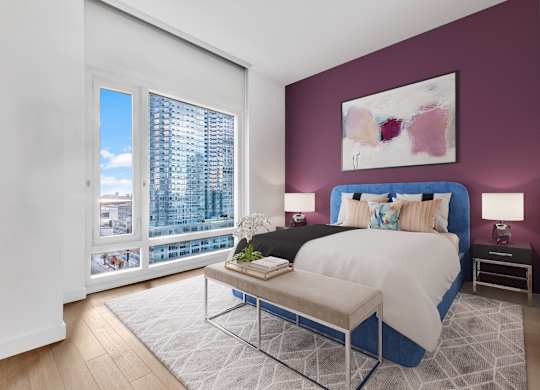 A bedroom with a large bed and a view of a city skyline.