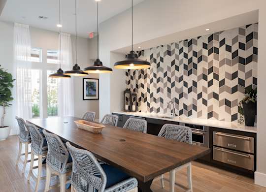 A modern dining room with a long wooden table and grey chairs at 55 Fifty at Northwest Crossing, Houston, TX 77092
