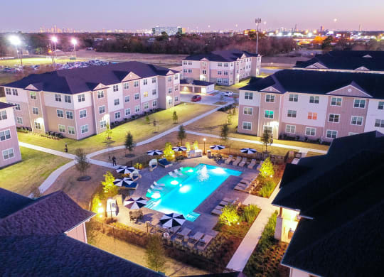 an aerial view of a resort style swimming pool at night at 55 Fifty at Northwest Crossing, Texas