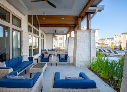 a patio with blue couches and chairs and a pool in the background at 55 Fifty at Northwest Crossing, Texas, 77092