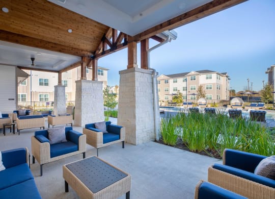 a patio with blue couches and chairs and a pool in the background at 55 Fifty at Northwest Crossing, Houston, TX