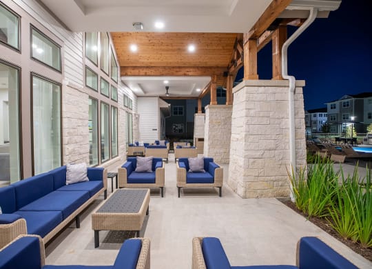 a patio with blue couches and chairs and a pool in the background at 55 Fifty at Northwest Crossing, Houston, 77092