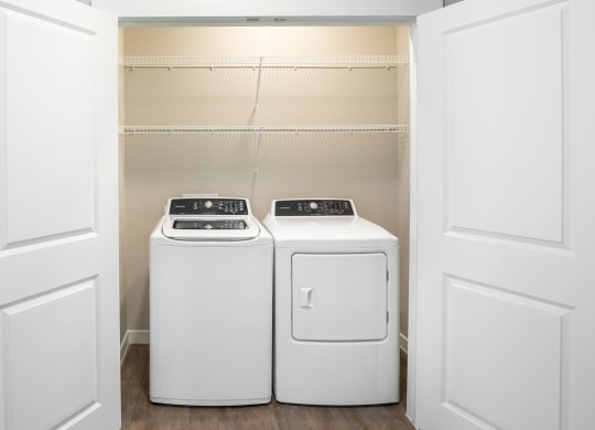 a washer and dryer in a laundry room with white doors at 55 Fifty at Northwest Crossing, Texas, 77092
