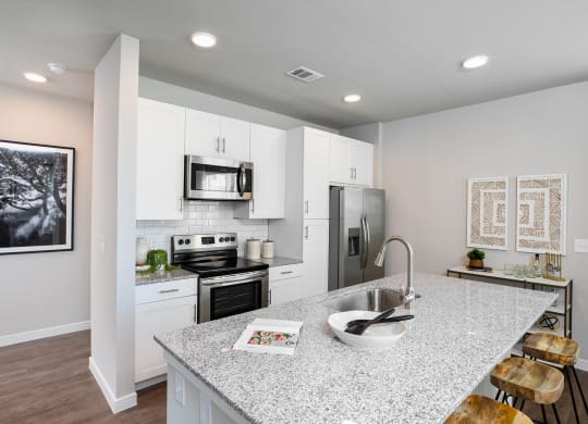 a kitchen with white cabinets and a granite counter top at 55 Fifty at Northwest Crossing, Houston, TX
