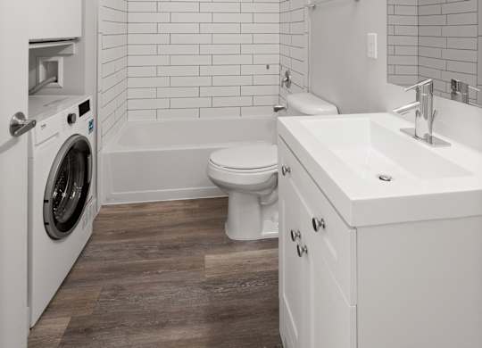 1-bedroom apartment at Bodde-88 with modern finished bathroom with white vanity and quartz counter top, includes a washer and dryer and shower and tub combination