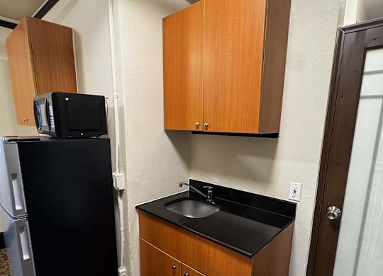 A small kitchen with a black fridge and a black counter top.