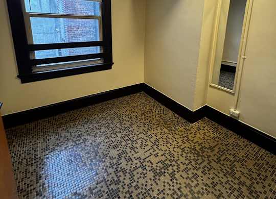 A room with a black and white tiled floor and a window.