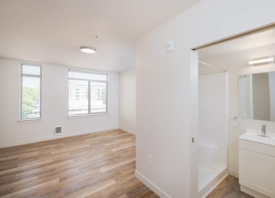A white bathroom with a wooden floor and a white sink.