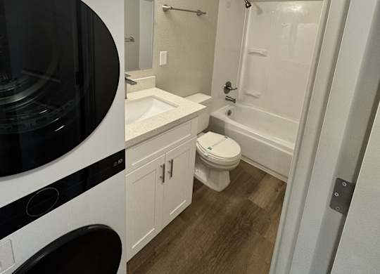 2-bedroom bathroom with a white & black washing machine and dryer and a shower & tub combination at Bridgeport Terrace Apartments
