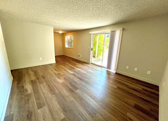 2-bedroom living room space at Bridgeport Terrace Apartments with wood plank vinyl floors and sliding glass window to patio.