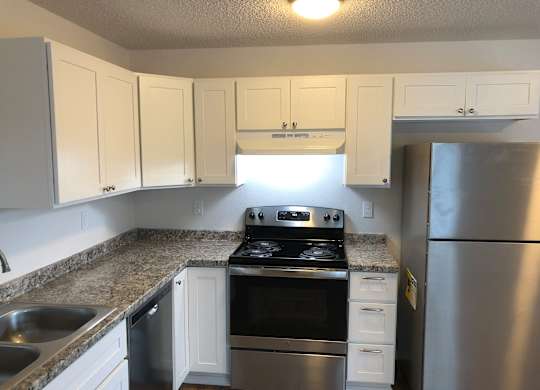 Studio kitchen with white cabinets and stainless steel appliances.