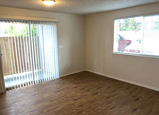 Studio living room with vinyl plank flooring and windows with blinds