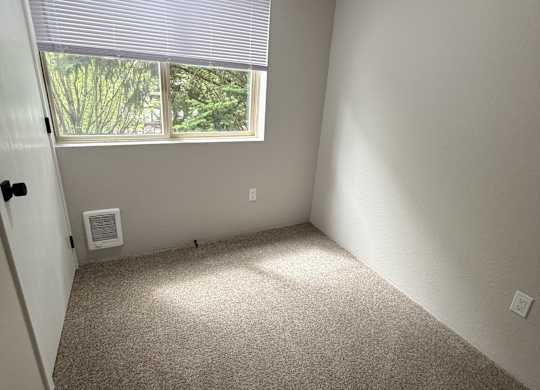 A room with a window covered by blinds and a door with a lock.