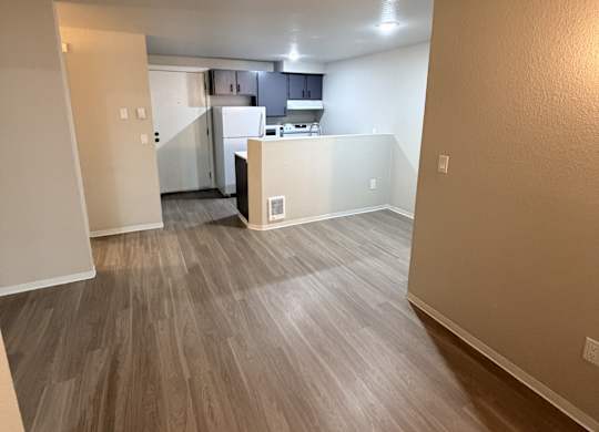 A kitchen area with a refrigerator, sink, and cabinets.