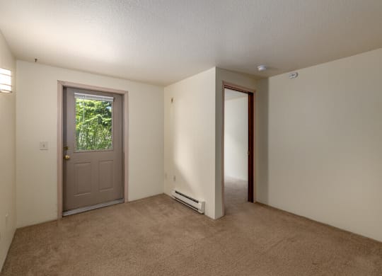A room with a carpeted floor and a door leading outside.