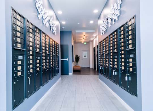 Hallway with a series of mailboes on both sides and a bench in the middle at Bode125 apartments