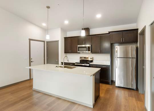 A modern kitchen with a white island and stainless steel appliances.