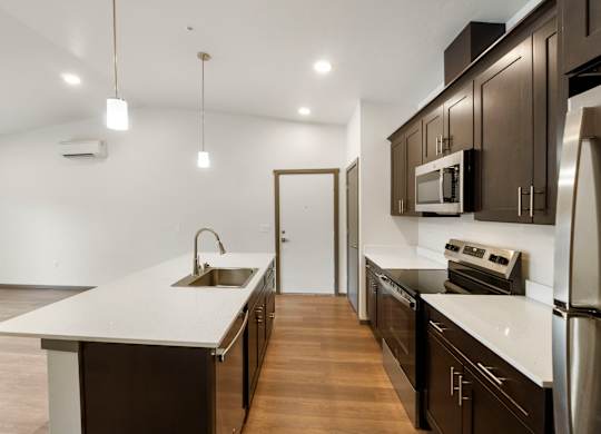 A modern kitchen with dark brown cabinets and white countertops.