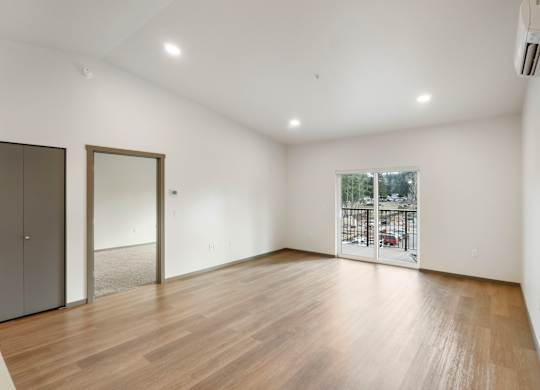 A room with wooden flooring and a window overlooking a parking lot.