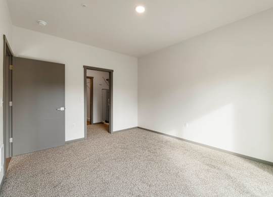 A room with a carpeted floor and two doors.