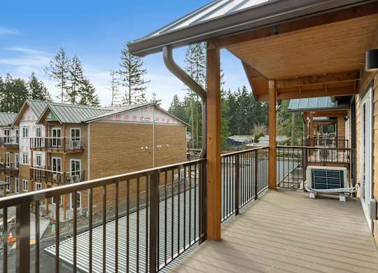 A wooden deck with a metal railing and a hot tub.