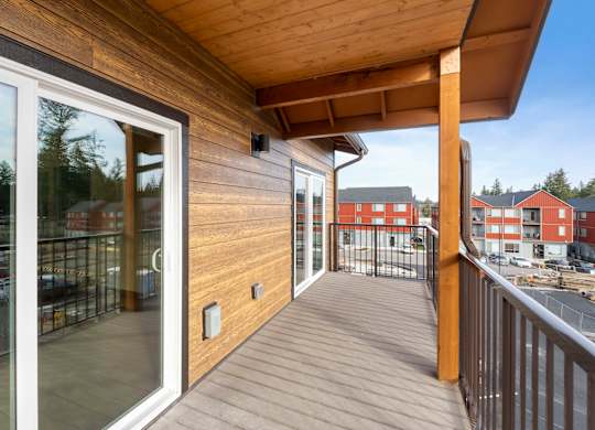 A balcony with a sliding glass door and a wooden railing.