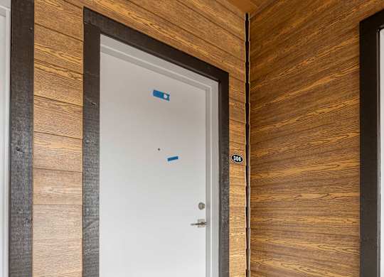 A white door is in a room with wooden walls.