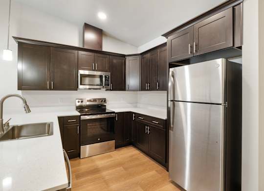 A modern kitchen with dark brown cabinets and stainless steel appliances.
