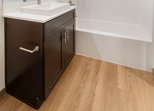 A modern bathroom with a white sink and black cabinetry.
