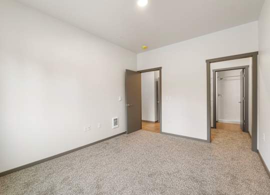 A room with a carpeted floor and three doors.