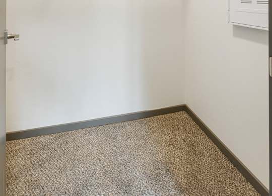 A walk-in closet with a metal rack and a carpeted floor.