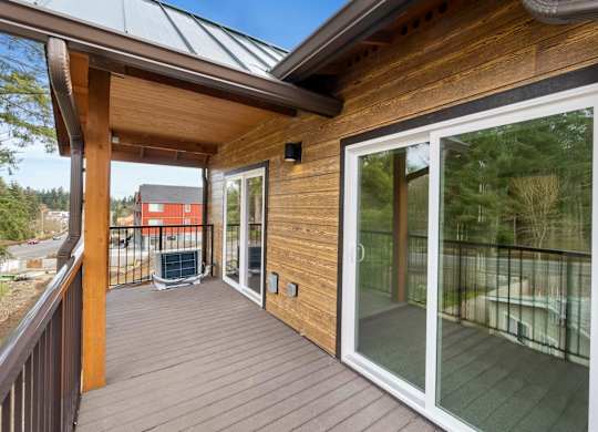 A wooden deck with a glass door leading to a backyard.