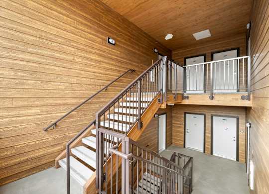 A wooden staircase with metal railings leads to a second floor.